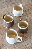 Four handmade ceramic cups on a wooden table