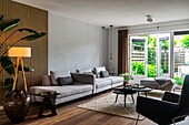 Living room with grey sofas, wooden accent wall and view of the garden