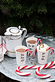 Hot chocolate with candy canes in Christmas-labelled paper cups