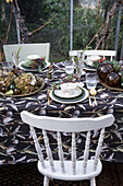 Table with floral patterned tablecloth and decoration made of natural materials in the winter garden