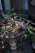 Winter bird bath decorated with dried flowers and moss in the garden