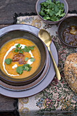 Pumpkin soup with relish, fresh cilantro and bread rolls