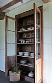 Vitrine aus Holz mit Geschirr und Gläsern im Landhausstil