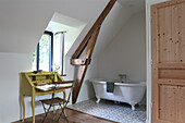 Freestanding bathtub and yellow secretary in the attic