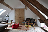 Living room in the attic with wooden beams and vintage armchairs