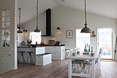 Open-plan kitchen with white wood paneling and wooden floor