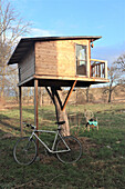 Modern wooden tree house with balcony in the autumn garden
