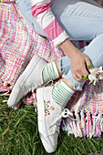 Gestreifte Socken und bestickte weiße Sneaker auf farbenfroher Picknickdecke im Garten