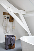 Basket with towel in bathroom with sloping ceiling and exposed wooden beams