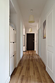 Long hallway with wooden floor and white walls in a flat