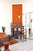 Living room with fireplace and orange-colored wall, rustic wooden decorations