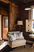 Wood-panelled living room with beige armchair and floor lamp