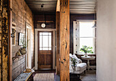 Entrance area with wooden walls and rustic beams, next to a cosy seating area by the window