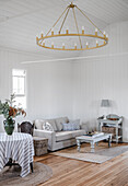 Living room in white with grey furniture and large chandelier