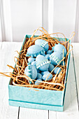 Light blue Easter eggs decorated with lace ribbon in a turquoise box on a wooden table