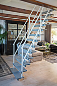 Cantilevered staircase in living room with wooden beamed ceiling