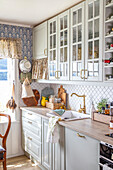 Landhausküche mit hellen Fronten und gemusterter Tapeten