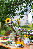 Sommerlicher Gartentisch mit Blumenstrauß und Kuchen