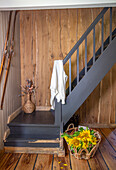 Rustic staircase, wooden wall panelling and sunflowers in a wicker basket