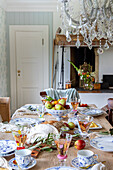 Festively laid wooden table with fruit and porcelain crockery in the dining room