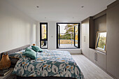 Double bed with patterned bed linen in bedroom with balcony