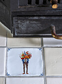 Tile with hand-painted motif in front of a stove