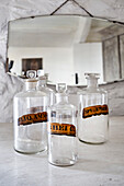 Antique apothecary bottles in front of a mirror