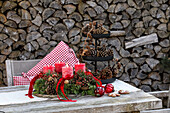 Wooden table decorated for Christmas with an Advent wreath, red candles and cone decorations