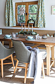 Bright dining area with wooden table and rattan chairs, Advent arrangement in the centre
