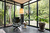 Winter garden with dark green upholstered armchair and large indoor plants