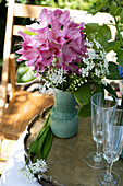 Bouquet of rhododendrons and wild garlic in a green vase on a garden table