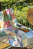 Patchwork quilt on a vintage iron bench in a blooming garden