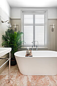 Freestanding bathtub, marble tiles and large indoor plant