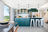 Modern kitchen with blue-green cabinet fronts and white bar stools