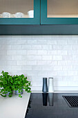 Modern kitchen with blue-green cabinet front and white tiled splashback