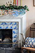 Decorated fireplace with Delft tiles and chair with cushions