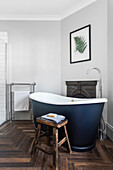 Freestanding bathtub in modern bathroom with herringbone-look floor