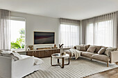 Living room with sofas in white and light brown, modern coffee table on a large carpet