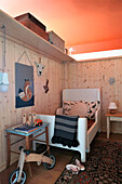 Children's room with wooden panelling, balance bike and wall decoration