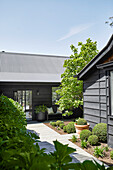 Manicured courtyard with boxwood balls and modern wooden house