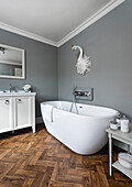 Modern bathroom with free-standing bathtub and herringbone-style flooring