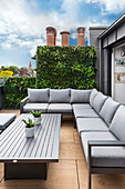 Corner sofa and table on a modern roof terrace with vertical greenery
