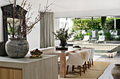 Dining area with wooden table and upholstered chairs, terrace with pool