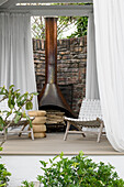 Terrace with fireplace, white curtains and woven chairs