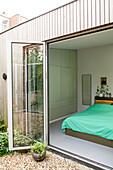 Bedroom with green wall unit and access to the garden