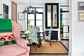 Dining room with patterned chairs and pink wing chair in the foreground