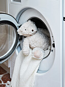 Cuddly soft teddy bear and towel in open washing machine