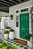 Green front door, plant pots and chequerboard tiles on the veranda