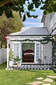 Veranda with flowering vines and view into bedroom with antique double bed