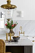 Kitchen with marble splashback, brass accents and flower vase